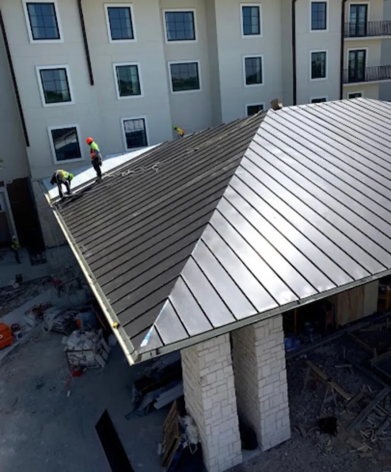 Crew installing standing seam metal roof panels on a commercial project in Corpus Christi